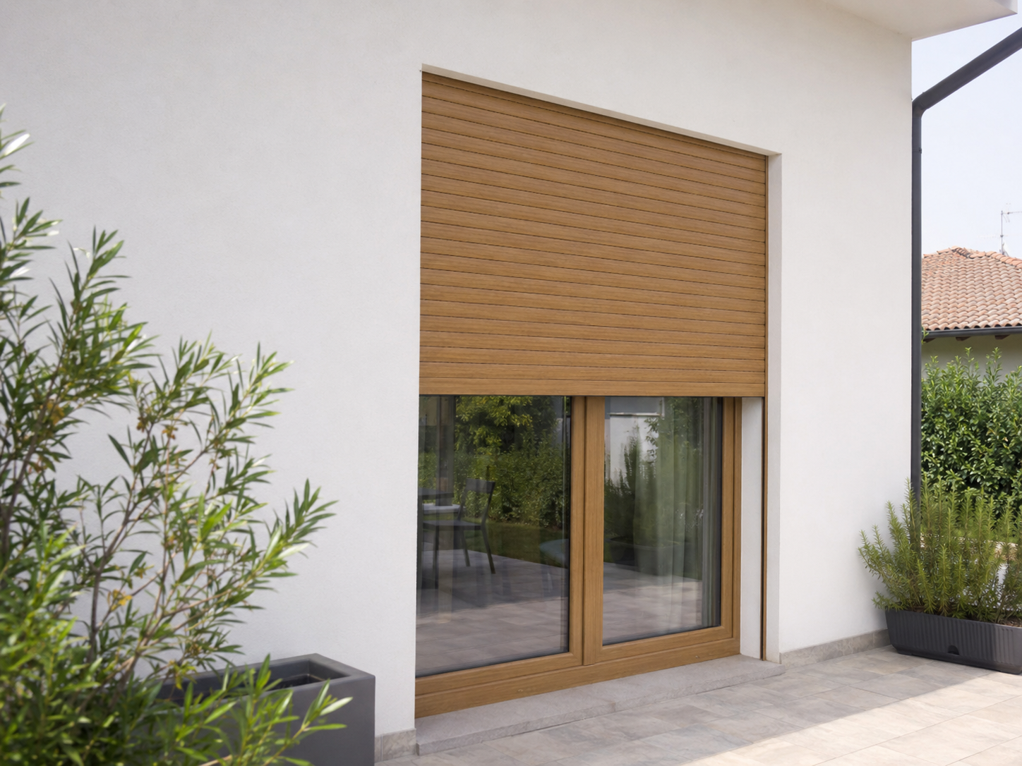 Avvolgibile in alluminio effetto legno rovere naturale abbassato a metà su una portafinestra a tutta altezza affacciata su un terrazzo